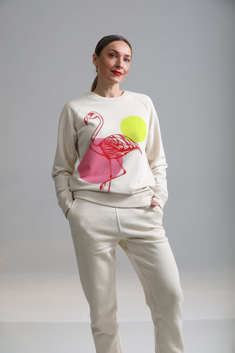 Model wearing a cream tracksuit with a flamingo illustration on the chest area, by fauna.ie