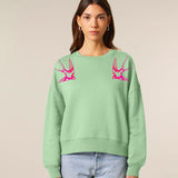 Person wearing a light green sweatshirt with pink swallows by fauna.ie